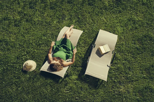 Mujer acostada en una tumbona con libro —  Fotos de Stock