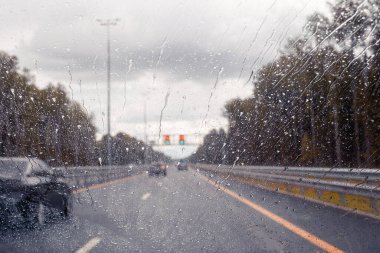 Hız limiti işaretli yol manzarası araba ön camından geçerken yağmur damlaları hızlanırken. Odaklanmamış otoyol. Sonbahar