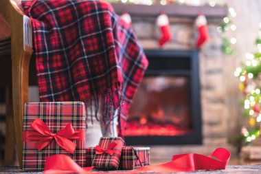 Kış çoraplarıyla kaplı kadın bacakları ekoseli oturma ve şöminenin yanındaki koltukta rahatlama ve aile için Noel ağacı paketleme kutuları. Alt görünüm.