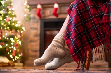 Örgü çorap giymiş kadın bacakları Noel ağacı ve şöminenin yanındaki koltuğa oturmuş. Alt görünüm 