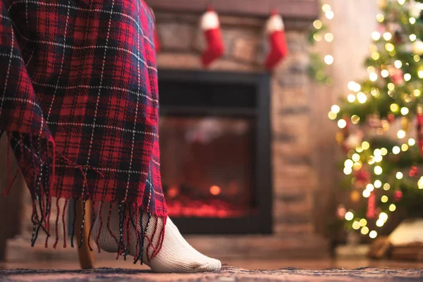 クリスマスツリーと暖炉の近くに再生覆われたアームチェアに座ってニット冬の靴下で障害のある女性の足の下のビュー 下の図 — ストック写真