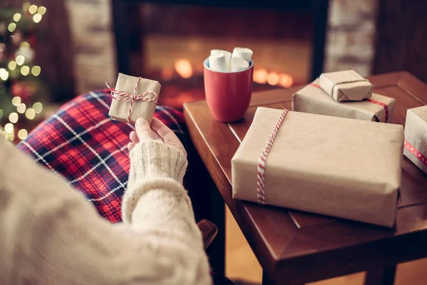 女性は 家族のためのギフトボックスを梱包した後 ココアとマシュマロのカップでお別れとクリスマスツリーの近くに座ってリラックスを果たしました — ストック写真
