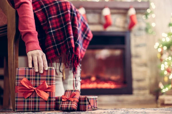 暖炉やクリスマスツリーの近くで演奏されたアームチェアに座っている障害のある女性の靴下の足や家族のためのパッキングギフトボックス 下の図 — ストック写真