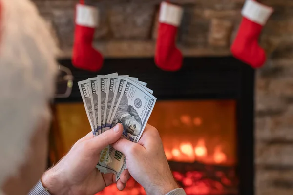 Man Räknar Amerikanska Dollar Sittande Nära Julgran Och Öppen Spis — Stockfoto