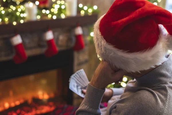 Грустный Человек Шляпе Санта Клауса Думает Считая Американские Доллары Сидящие — стоковое фото