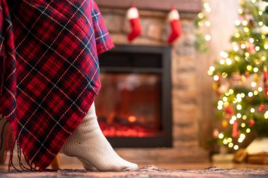 Kış çoraplı, kötürüm kadın bacakları Noel ağacı ve şöminenin yanındaki koltuğa oturmuş. Alt görünüm 
