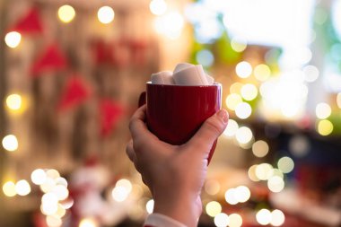 Küçük ev kakaosu barının karşısındaki Noel zamanı elinde bir fincan sıcak kakaolu marshmallowlu kadın eli..