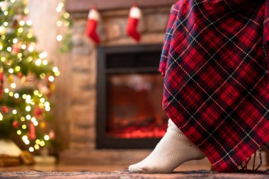 Örgü çorap giymiş kadın bacakları Noel ağacı ve şöminenin yanındaki koltuğa oturmuş. Alt görünüm 