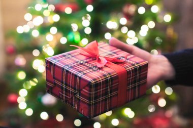 Adam yılbaşı ve yeni yıl hediyesi kutusunu parlayan ampulleri olan bir kadına veriyor. Xmas konsepti. Kapatın. Seçici odak