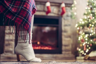 Örgü çorap giymiş kadın bacakları Noel ağacı ve şöminenin yanındaki koltuğa oturmuş. Alt görünüm 