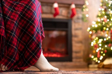Örgü çorap giymiş kadın bacakları Noel ağacı ve şöminenin yanındaki koltuğa oturmuş. Alt görünüm 
