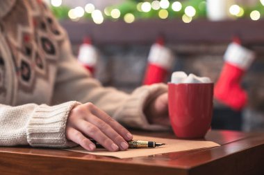 Noel Baba 'ya mektup yazan kadın, Noel' de şöminede ampullerin süslenip sıcak kakao ve lokum içilen dolmakalemle kağıt üzerine dolmakalem kullanıyor..