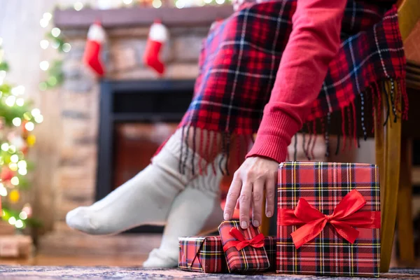 冬の靴下の女性の足は 暖炉の近くのアームチェアに座ってリラックスし 家族のためのクリスマスツリーのパッキングギフトボックスを果たしました 下の図 — ストック写真