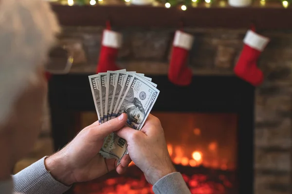 Man Räknar Amerikanska Dollar Sittande Nära Julgran Och Öppen Spis — Stockfoto
