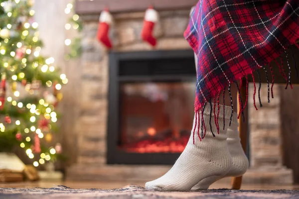 クリスマスツリーと暖炉の近くに再生覆われたアームチェアに座ってニット冬の靴下で障害のある女性の足の下のビュー 下の図 — ストック写真