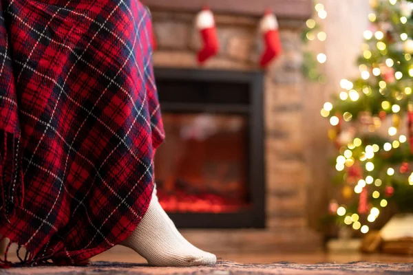 クリスマスツリーと暖炉の近くに再生覆われたアームチェアに座ってニット冬の靴下の女性の足の下のビュー 下の図 — ストック写真