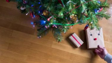 Kadınların el yapımı hediyeleri Noel ağacının altındaki bir kağıda sardıkları orijinal zaman atlamalı video. Aileye hediyeler. Üst görünüm.