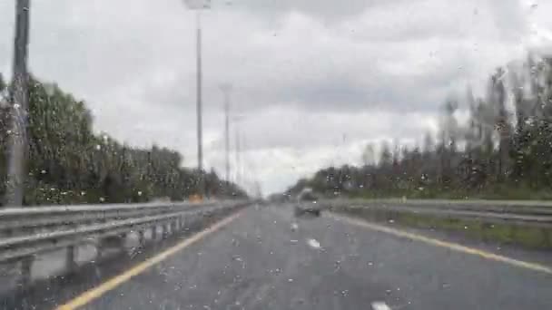 速度で運転中に雨滴を行くとフロントガラスの車の窓からの道路ビューの元のタイムラプスビデオ 集中していない高速道路 — ストック動画