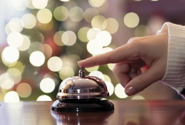 Noel seyahati. Misafir masasında misafir çanı çalıyor ve arka plandaki Noel ağacında renkli çelenkler parlıyor. Otel, restoran..