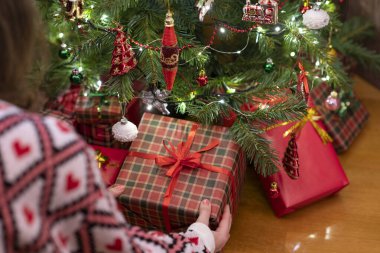 Hediye kutusunu Noel ağacının altına koyan kadın. Aile için hediyeler. 