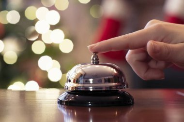 Misafirlerin eli Noel 'de misafir odasının masasında zili çalar. Arka plandaki Noel ağacında parlak bir çelenk. Seyahat kavramı. 