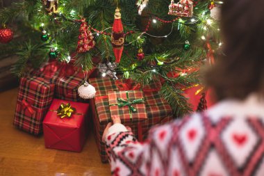 Hediye kutusunu Noel ağacının altına koyan kadın. Aile için hediyeler. 