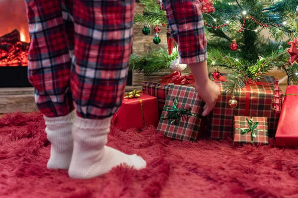 クリスマスツリーの下にギフトボックスを置くパジャマと冬の靴下の女性 家族へのプレゼント — ストック写真