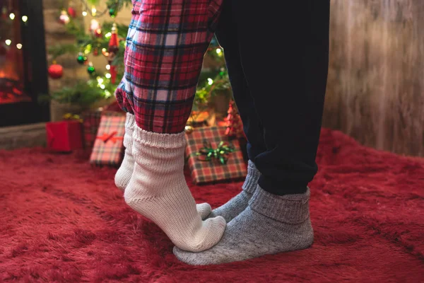 冬の靴下の先端のつま先に立つ女性の足は クリスマスツリーの近くのふわふわした赤い毛布の上に男性の袋に贈り物が付いています コンセプト — ストック写真