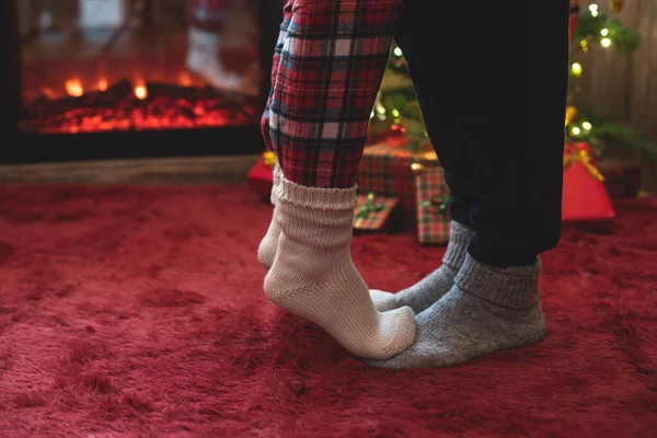 冬の靴下の先端のつま先に立つ女性の足は クリスマスツリーの近くのふわふわした赤い毛布の上に男性の袋に贈り物が付いています コンセプト — ストック写真
