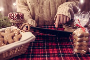 Noel pastanesi. Kadın satıcı, garson, bilgisayar kullanarak zencefilli ekmek, marşmelov, kurabiye, şeker ve sıcak çikolata satan küçük bir kafede..