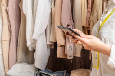 Kadın girişimci moda giyim mağazasında envanter sayımı yaparken elinde tablet tutuyordu.