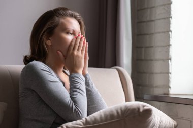 Üzgün, korkmuş, elleriyle yüzünü kapatıp ağlayan bir kadın. Yalnız kız, pencerenin yanında oturuyor, yastıkla apartman dairesinde..