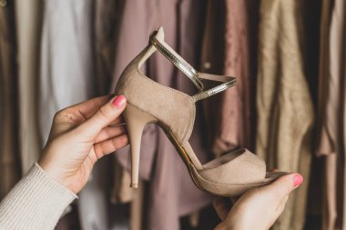 Dolaptaki yüksek topuklu ayakkabıları ve kıyafetleri seçen bir kadın. Sezon konsepti