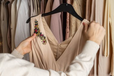 Kadın alışverişçi, müşteri şık bir elbise seçiyor. Modern yaz ve sonbahar kıyafetleri mağazasında çeşitli kadın kıyafetleri. Alışveriş..