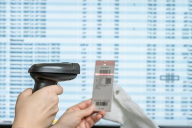 Bir depo çalışanı, kadın bluzunun fiyat etiketinden barkod tarayıcısı kullanarak giysileri kabul ediyor ve bilgisayar tabanına ekliyor..