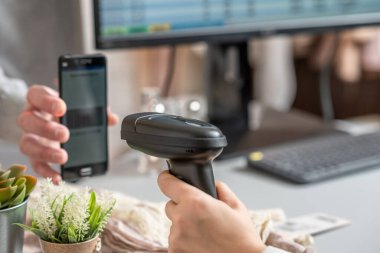 Kadın giyim mağazasından hediye alan bir adam. Kadın kasiyer, satıcı QR kodunu alıcı telefonundan tarıyor kasada elle tarayıcı kullanarak..