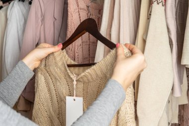 Kadın alışverişçi, kıyafet seçen müşteri. Modern yaz ve sonbahar kıyafetleri mağazasında çeşitli kadın kıyafetleri. Alışveriş..