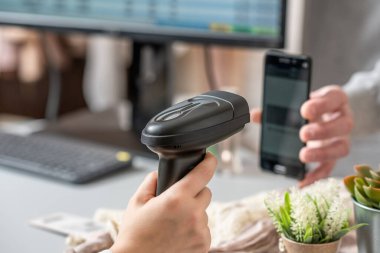 Kadın kasiyer, barkod tarayıcı kullanarak QR kodunu alıcıdan tarıyor. Erkek, kadın giyim mağazasından reklam kodu kullanarak hediye alıyor.. 