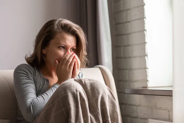 Zieke Brunette Vrouw Niezen Zitten Bank Woonkamer Buurt Van Raam — Stockfoto