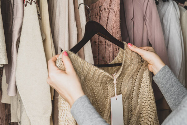 Woman shopper, customer choosing clothes. Assortment of female modern summer and autumn clothing in garment store. Shopping.