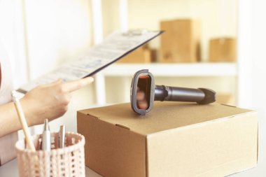 Küçük bir ofiste pano ve barkod tarayıcı ile küçük bir işletme kuran kadın sahibi. Depo çalışanı.