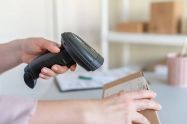 Postanenin kadın çalışanı. Müşteri gönderdiğini onaylamak için barkod tarayıcısı kullanıyor. Ev teslimat servisi.