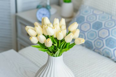 Oturma odasındaki sehpanın üstünde beyaz vazodaki laleler çiçek açıyor. Buket besteliyorum. Durgun hayat