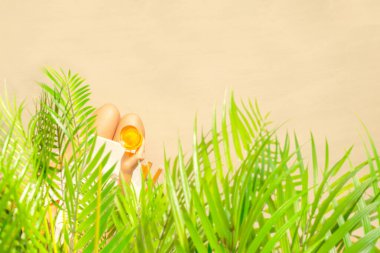 Bir bardak portakallı suyla palmiye dallarının altında oturan yalnız bir kadın. Yaz tatilinde kumsalda bir kadının dinlenmesi. Üst görünüm