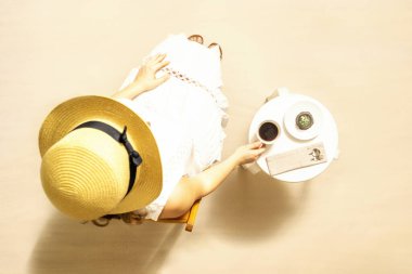 Plajda sıcak kahve ve çikolatalı kek içen bir kadın masada oturup egzotik yaz tatilinin tadını çıkarıyor. Açık hava kafesi. Üst görünüm