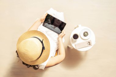 Tabletli bir kadın, açık hava kafeteryasında, palmiye ağaçlarının altında oturmuş çikolatalı kek ile sıcak kahve içiyor. Üst görünüm