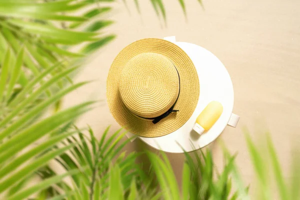 护肤防晒霜和草帽放在棕榈树林沙滩上的白桌上 顶部视图 — 图库照片