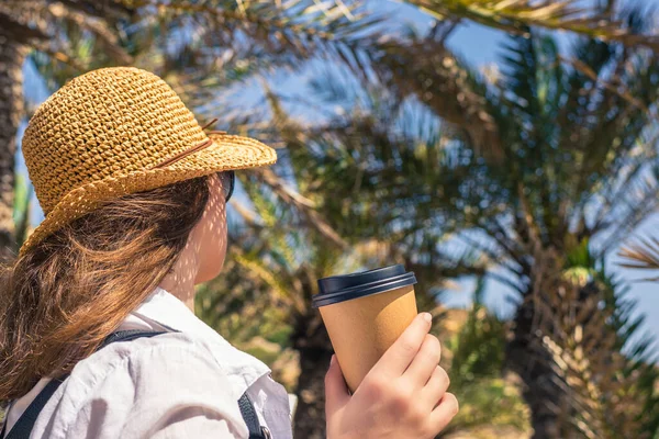 Вид Сзади Женщину Соломенной Шляпе Бумажной Чашкой Кофе Прогуливаясь Пальмовому — стоковое фото
