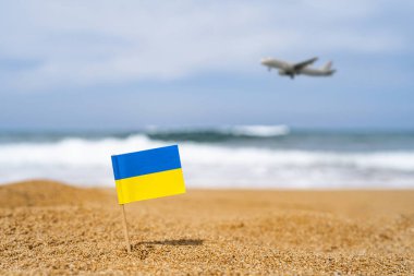 Ukrayna bayrağı sahilin karşısındaki kumsalda, iniş yapan uçakla birlikte bir kürdan şeklinde. Seyahat kavramı
