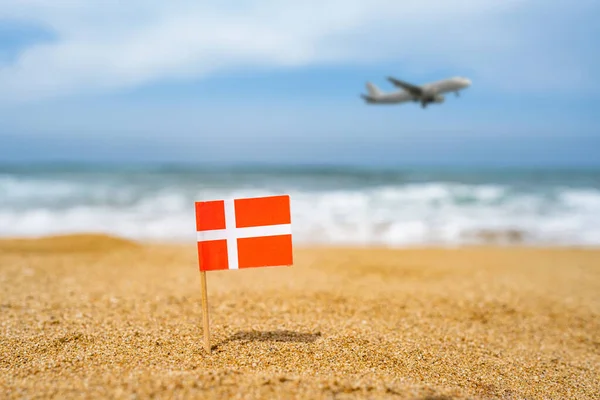 덴마크 국기는 착륙하는 비행기와 해변의 반대편 해변의 모래에서 이쑤시개 모양을 — 스톡 사진